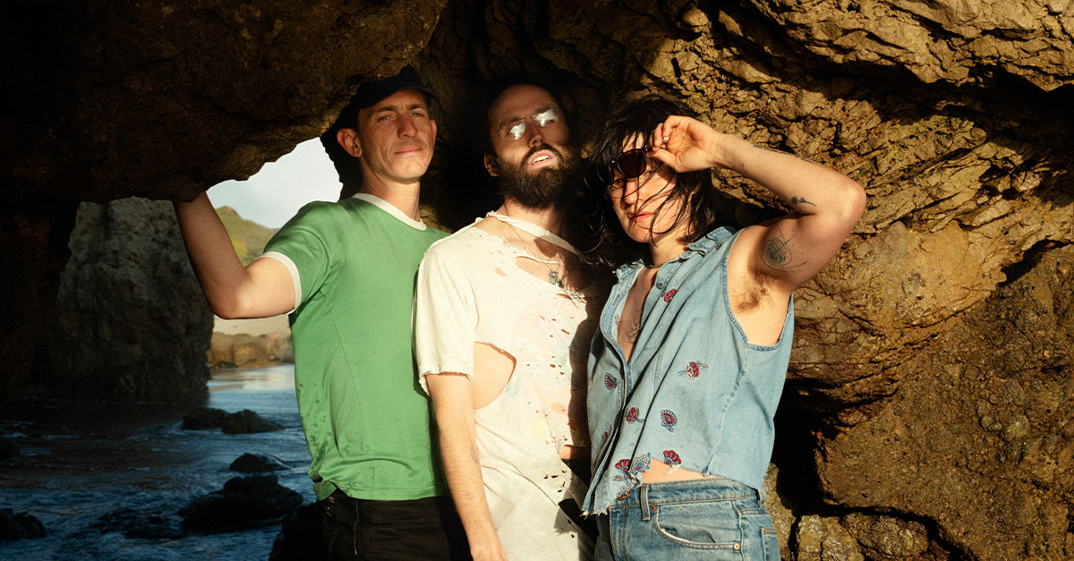 3 people standing in a cove by the ocean