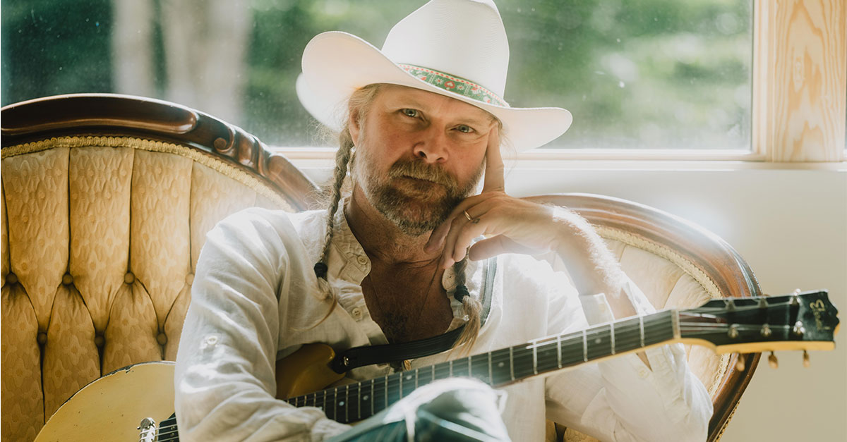 A man sitting in a chair with a guitar on his lap.
