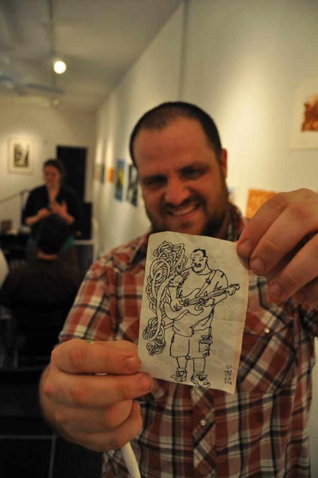 Philly ambient guitarist Dan Malloy poses with an illustration made by an audience member during his set at Highwire Gallery | Photo by John Vettese