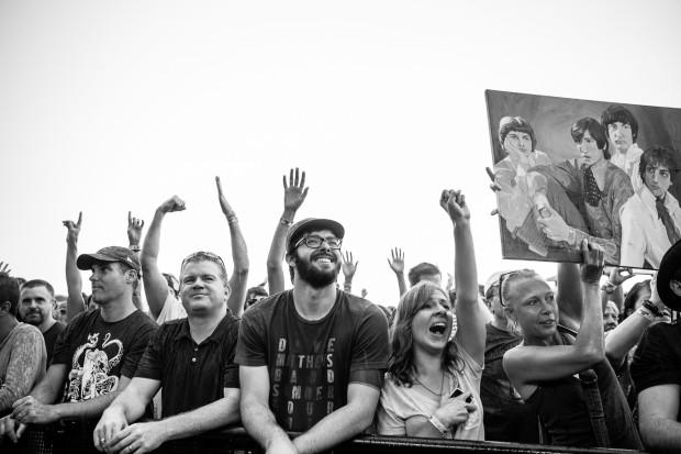 The crowd at Newport shakes fists and waves oil paintings of The Beatles | Photo by Kate McCann