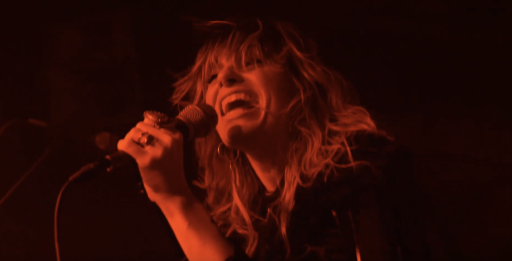 Ruby The Hatchet rages under red lights in the concert-shot music video for “The Change”